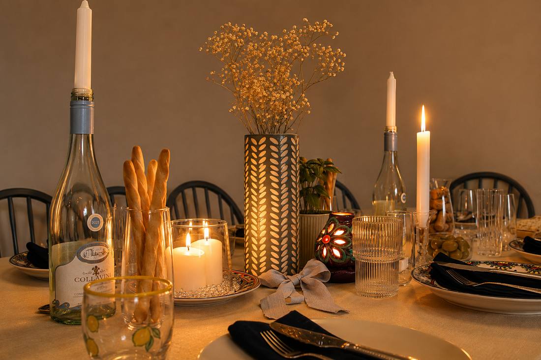 A candlelit dinner table with breadsticks, wine, and a patterned vase