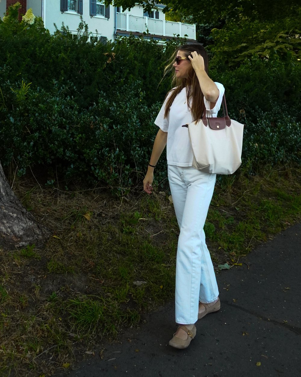Katya walking on a tree-lined street in summer