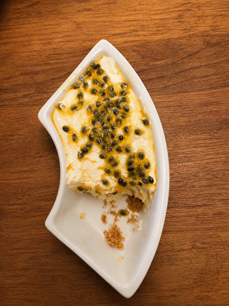 A cottage cheesecake cup topped with passion fruit, half eaten
